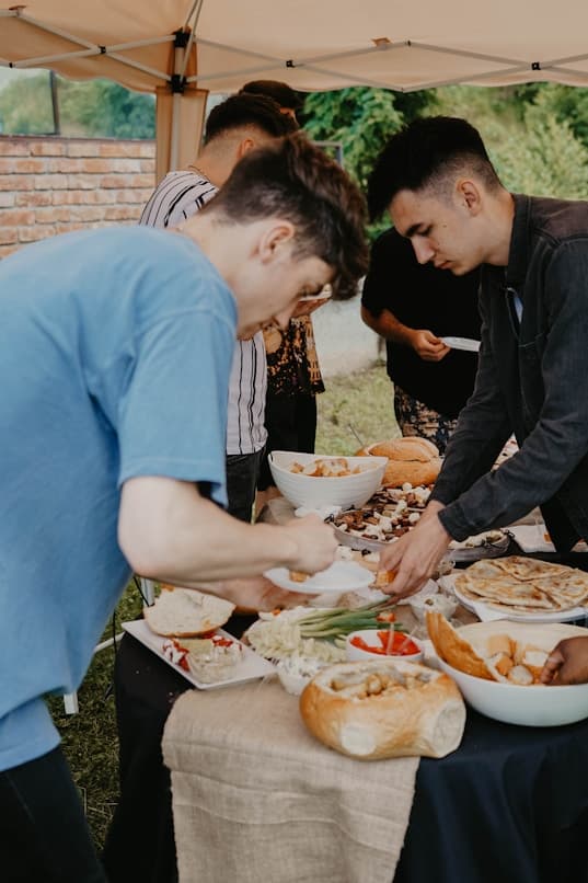 Friends gathered around a long table sharing food outdoors